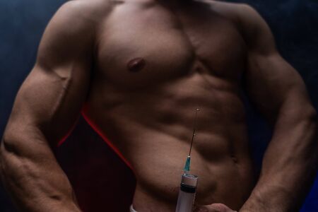 Bodybuilder holding big syringe with injection. concept of steroid in the sport and addiction.の写真素材