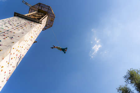 Sportsman climber training outdoor with blue sky , climbing on artificial colourful rock wall. Healthy lifestyle and bouldering concept.の写真素材