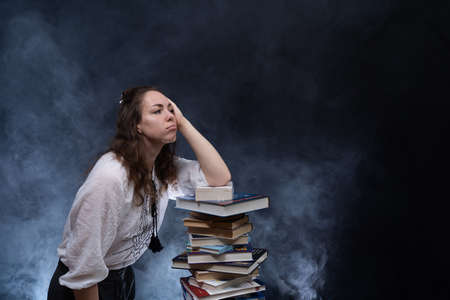 Sad female student reading with lots of books for the exam. Concept home education.の写真素材