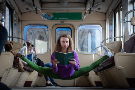 Girl sitting on the split in the subway car and reading book.の写真素材