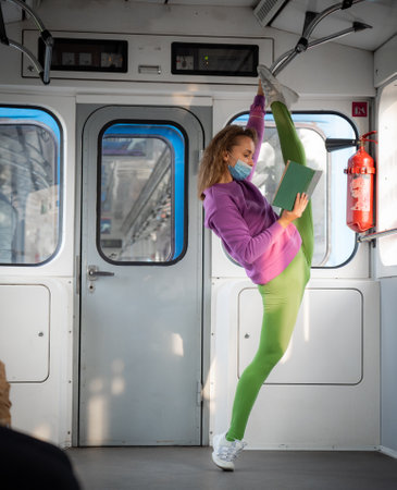 Very flexible woman wearing mask reading book in the subway car sitting in the gymnastic split.の写真素材