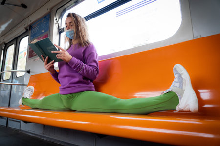 Very flexible woman wearing mask reading book in the subway car sitting in the gymnastic split.の写真素材