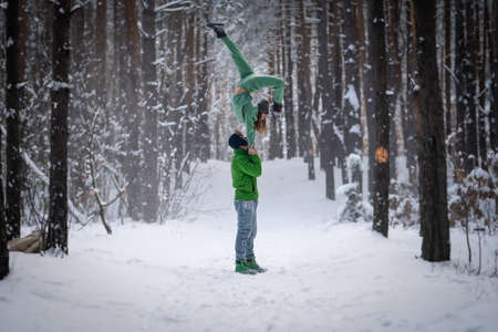 Acrobatic duo making nice pose in the snowy forest during the winter. Concept relationship, happiness and trustの写真素材
