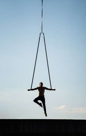 Man doing exercise outdoor on blue sky background. Concept calisthenic, workout and healthy lifestyleの写真素材