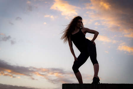 Female dancer on the edge of rooftop on the sky background. Concept of healthy lifestyle, talent and aspirationの写真素材