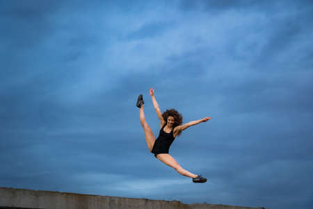 Super flexible woman jumping on the sky background. Concept of healthy lifestyle, happiness and joyの写真素材