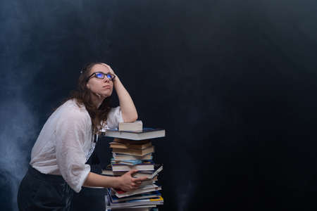 Sad female student reading with lots of books for the exam. Concept home education.の写真素材