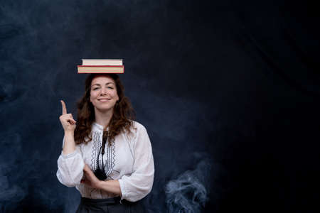 Girl holding books on the head. Concept of genius, meditation and knowledgeの写真素材