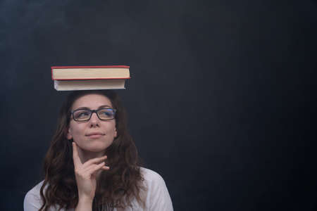 Girl holding books on the head. Concept of wisdom, knowledge and self-educationの写真素材