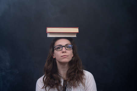 Girl holding books on the head. Concept of wisdom, knowledge and self-educationの写真素材