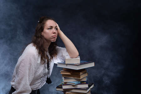 Sad female student reading with lots of books for the exam. Concept home education.の写真素材