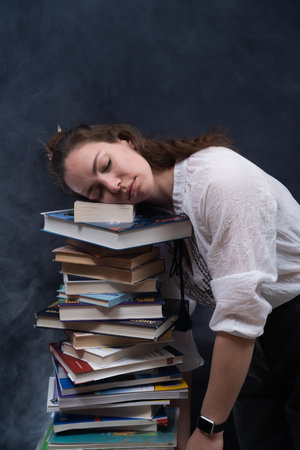 female student slipping on the lots of books before the exam. Concept home education.の写真素材