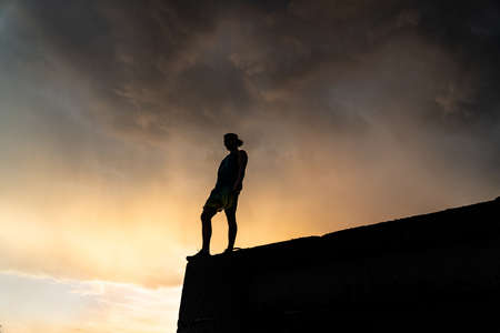 Silhouette of Man stepping from the edge during dramatic sunset. Concept goal, step forward and riskの写真素材