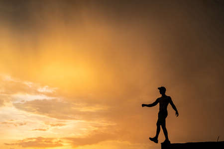 Silhouette of Man stepping from the edge during dramatic sunset. Concept goal, step forward and riskの写真素材