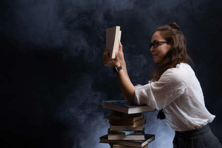 Sad female student reading with lots of books for the exam. Concept homeschoolingの写真素材
