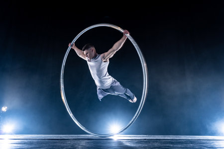 Cyr Wheel circus artist on smoked, dark background performing on stageの写真素材