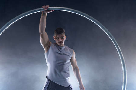 Cyr Wheel circus artist on smoked, dark background performing on stageの写真素材