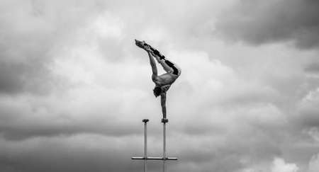 Man keeps balance on one hand on the cloudy sky background. Concept of yoga, meditation and healthy lifestyleの写真素材