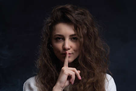 Pretty woman making silence sign with copy space on black backgroundの写真素材