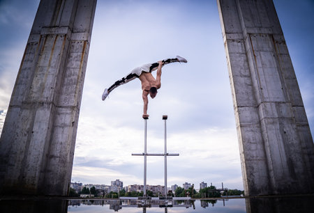 Flexible male circus Artist keep balance on one hand against amazing cloudscape and modern constructions . Individuality, creativity and modern point of view conceptの写真素材