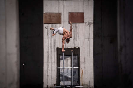 Flexible male circus Artist keep balance by one hand in the concrete structure. Individuality, outstanding and originality.の写真素材