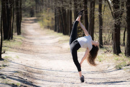 Flexible female gymnast makes exercise in the forest. Healthy lifestyleの写真素材