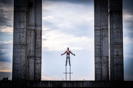 Man standing on the edge of rooftop unfinished building with dramatic clouds on background. Concept of Courage, inspiration and freedomの写真素材