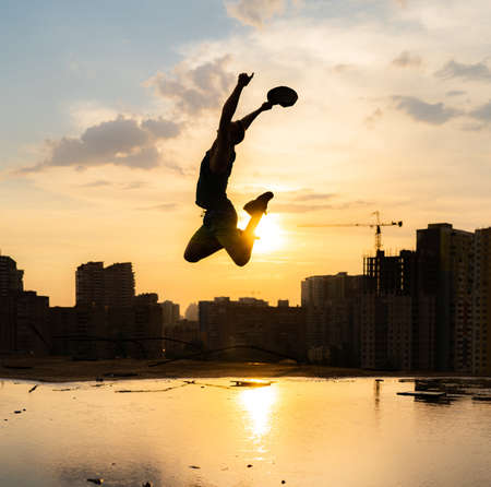 Silhouette of Man stepping from the edge during dramatic sunset. Concept goal, step forward and riskの写真素材