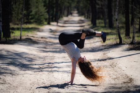 Flexible female gymnast makes exercise in the forest. Healthy lifestyleの写真素材