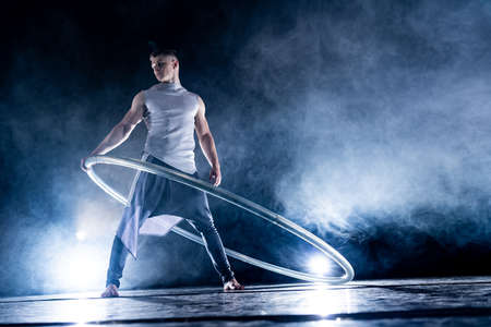 Cyr Wheel circus artist on smoked, dark background performing on stageの写真素材