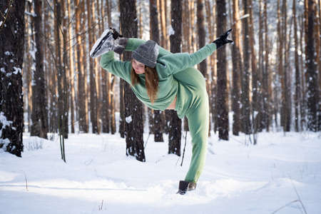 Super flexible woman doing split in the snowy park. Concept of healthy lifestyle, stretching and yogaの写真素材