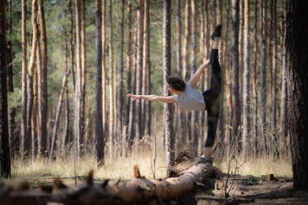 Flexible female gymnast makes exercise in the forest. Healthy lifestyleの写真素材