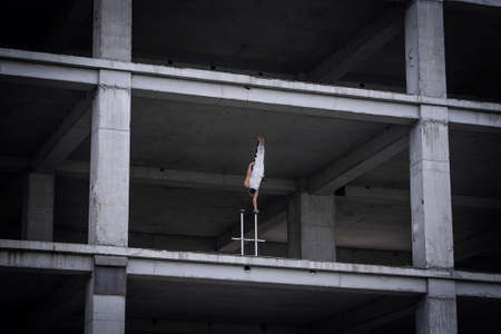 Flexible male circus Artist keep balance by one hand in the concrete structure. Individuality, outstanding and originality.の写真素材