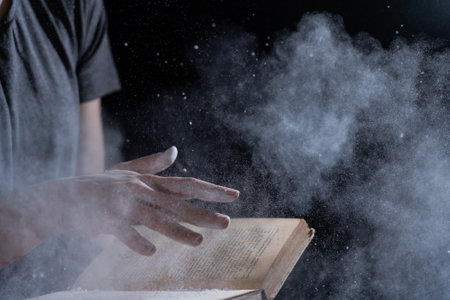 Hands hold Vintage open Book Glows on black background. Concept of mystery, riddle and secretの写真素材