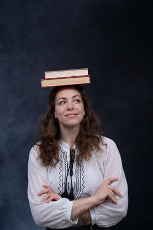 Girl holding books on the head. Concept of genius, meditation and knowledgeの写真素材