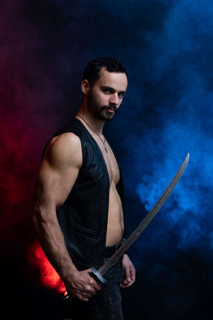 Muscular Man posing with long sword isolated on black and smoked backgroundの写真素材