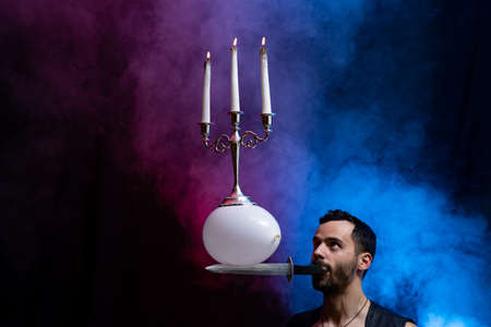 Circus artist holding knife in the mouth blow up balloon with candelabrum on it and catch it keeping in balanceの写真素材