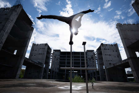 Flexible male circus Artist keep balance on one hand against amazing cloudscape and modern constructions . Individuality, creativity and modern point of view conceptの写真素材