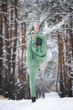 Super flexible woman doing split in the snowy park. Concept of healthy lifestyle, stretching and yogaの写真素材