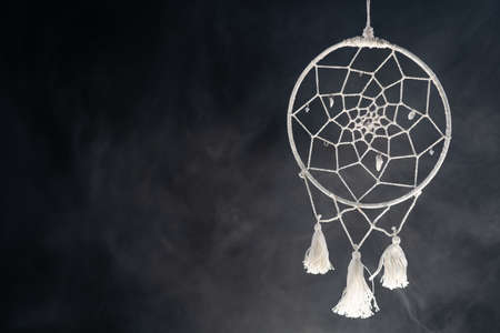 Mystical attribute dreamcatcher on a black background with smokeの写真素材