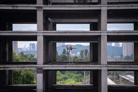 Flexible male circus Artist keep balance by one hand in the concrete structure on sky background with reflection in the water. Equality, consistency and symmetry concept.の写真素材