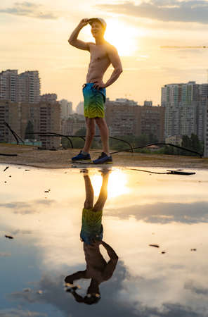 Muscular man with capping on the rooftop during sunset on cityscape backgroundの写真素材