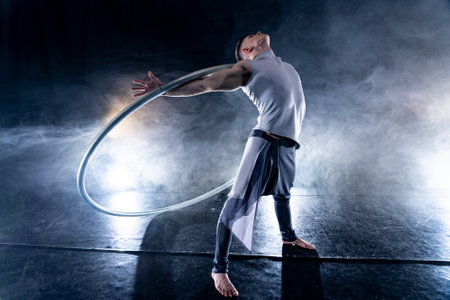 Cyr Wheel circus artist on smoked, dark background performing on stageの写真素材