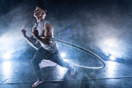 Cyr Wheel circus artist on smoked, dark background performing on stageの写真素材