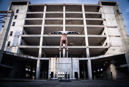 Flexible male circus Artist keep balance by hands in the concrete structure. symmetry and uniformity concept.の写真素材