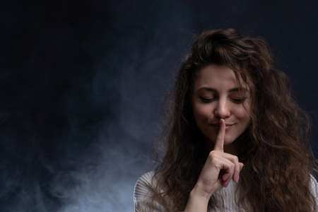Pretty woman making silence sign with copy space on black backgroundの写真素材