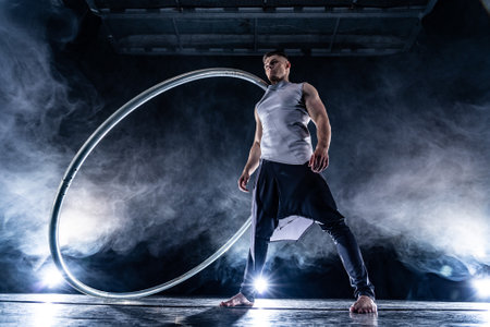 Cyr Wheel circus artist on smoked, dark background performing on stageの写真素材