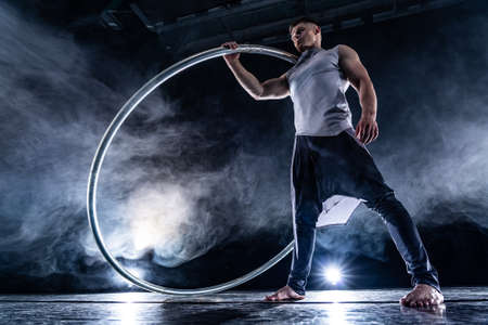 Cyr Wheel circus artist on smoked, dark background performing on stageの写真素材