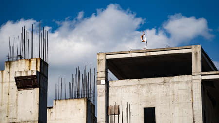 Flexible woman keep balance on one foot on the edge of building under construction. Risk, courage and chance conceptの写真素材