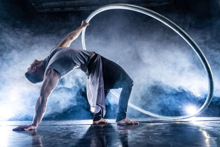 Cyr Wheel circus artist on smoked, dark background performing on stageの写真素材
